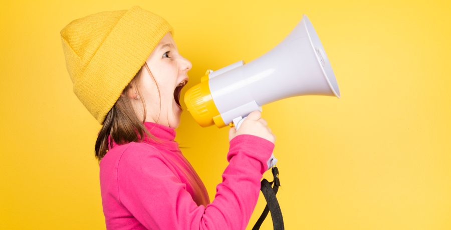 Ein Mädchen schreit in ein Mikrofon, Bild mit gelbem Hintergrund