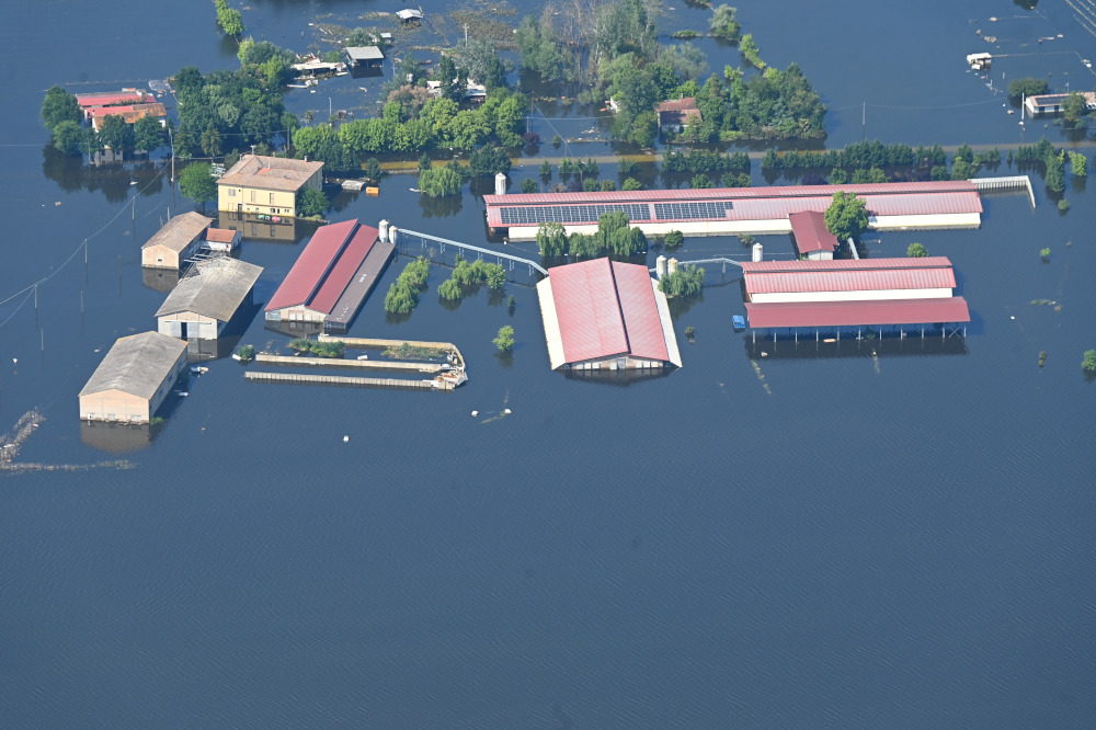 Luftaufnahme mehrerer Gebäude in der Region Emilia-Romagna die nach einer Überschwemmung unter Wasser stehen.