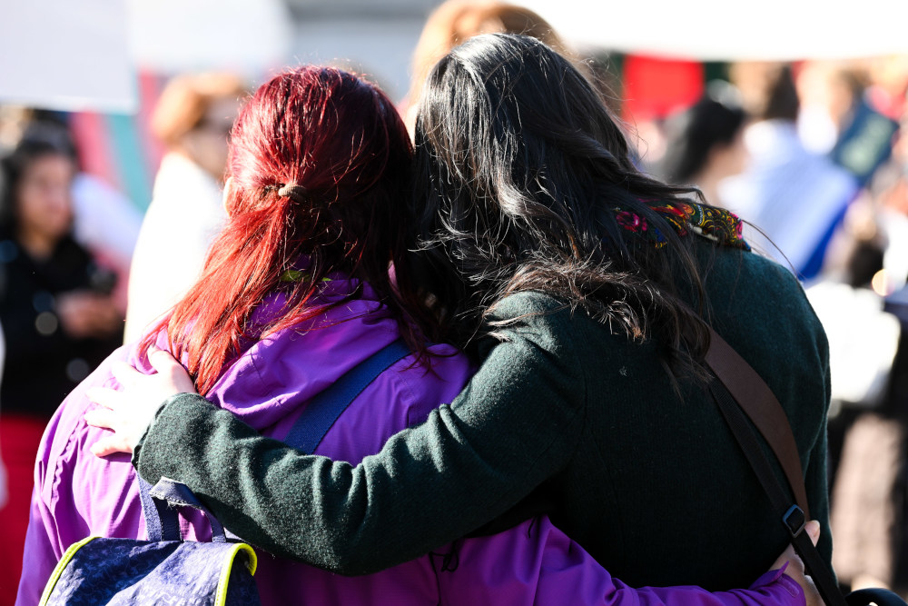Zwei Frauen umarmen sich bei einer Demonstration