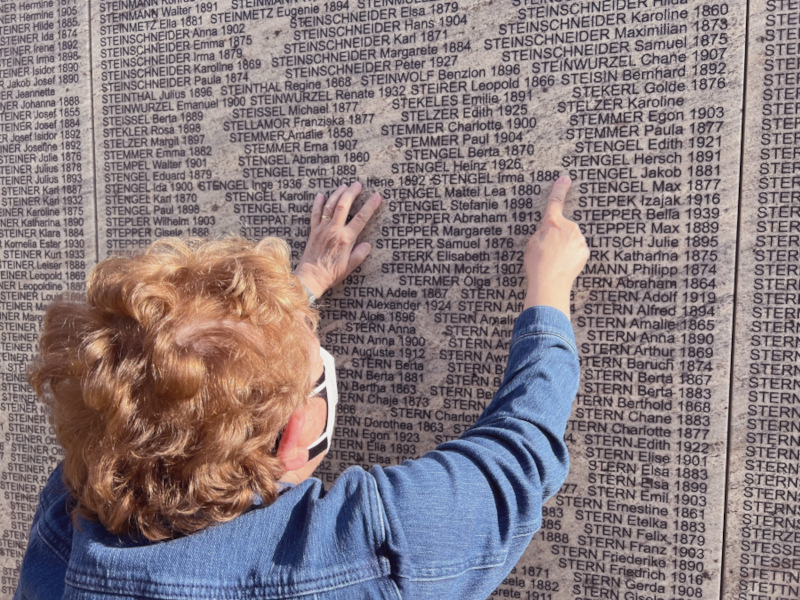 Foto: Edna Weissman Magder vor der Namensmauer in Wien. Sie zeigt auf den in der Namensmauer eingravierten Namen "Stengel Jakob".