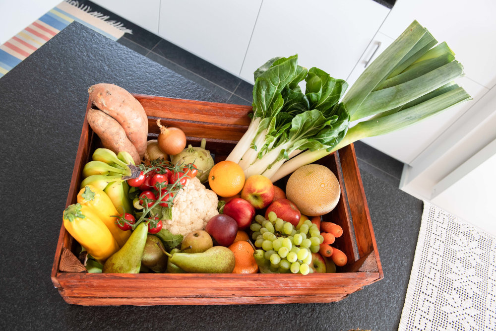 Eine Holzkiste in der sich Gemüse und Obst befindet.